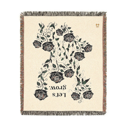Beige floral throw blanket with tassels, woven cotton blend with black rose and green leaf print