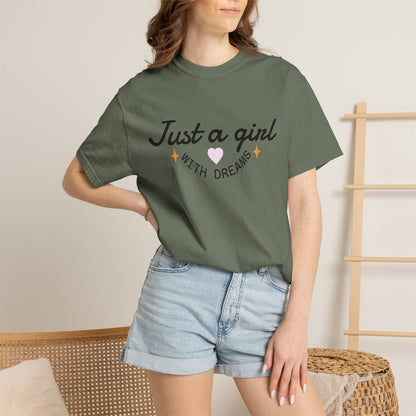 Woman wearing an olive green t-shirt with 'Just a girl WITH DREAMS' illustration and denim shorts.