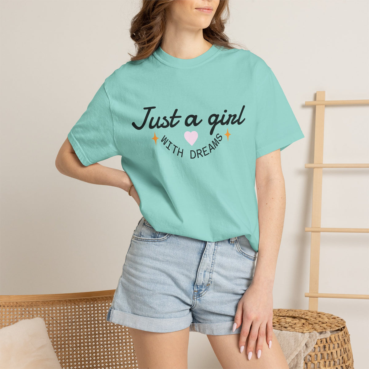 Woman wearing a light blue t-shirt with 'Just a girl WITH DREAMS' text and a pink heart.