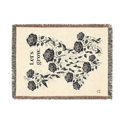 Beige floral throw blanket with black rose pattern and tassel fringe, cozy woven fabric