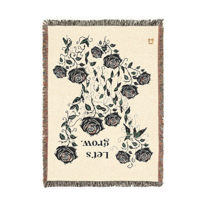 Ivory floral rug with black roses print and fringe edges, woven polyester