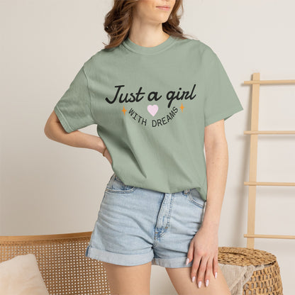 Woman wearing a sage green t-shirt with 'Just a girl with dreams' illustration and denim shorts.